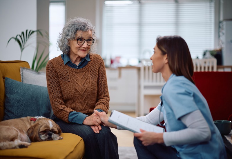 Happy senior woman talking to a caretaker who is visiting her at home