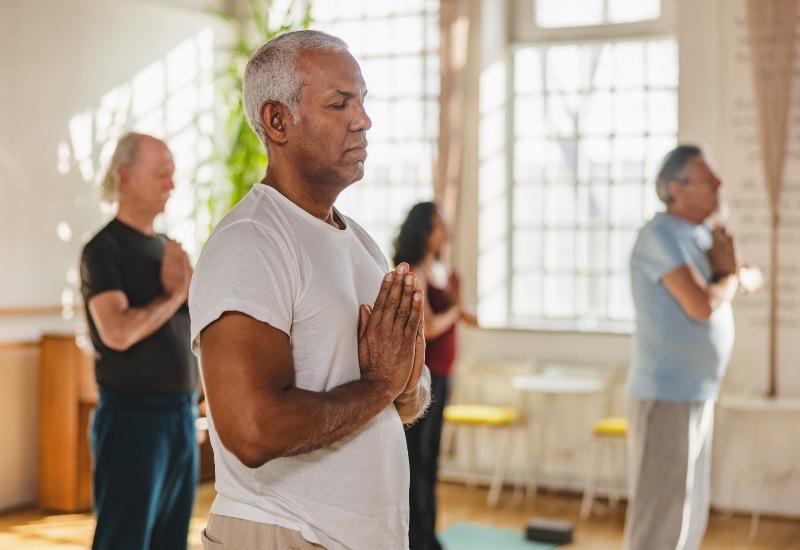 Group of adults practicing yoga in a bright studio, showing signs of mental health in Glenview, IL