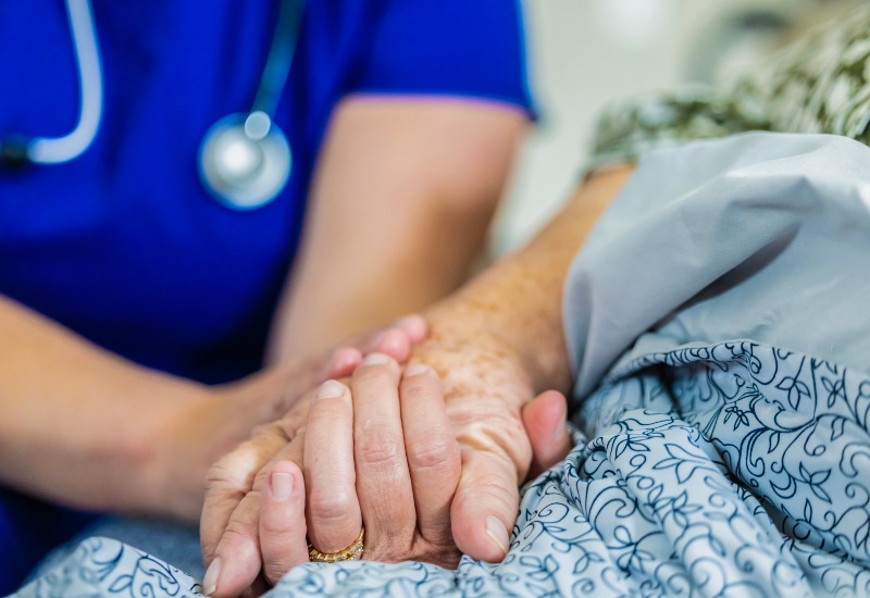 Healthcare worker holding a patient's hand in a home in Glenview, IL
