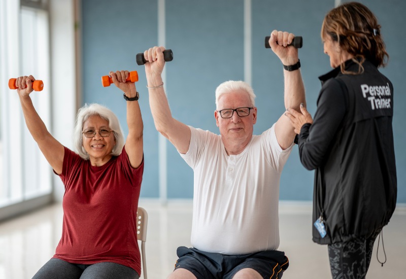 Personal trainer guiding two people lifting dumbbells during a workout in Glenview, IL