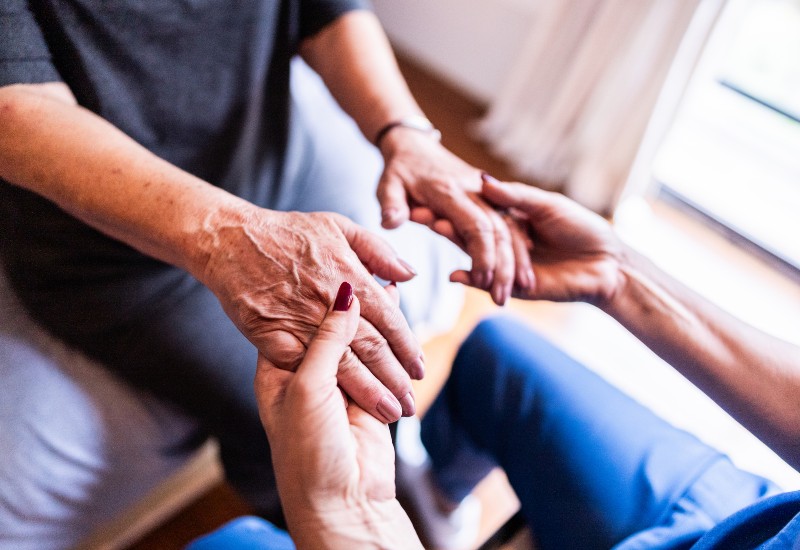 Close-up of home caregiver and senior woman holding hands for Parkinson's in Glenview & Northbrook