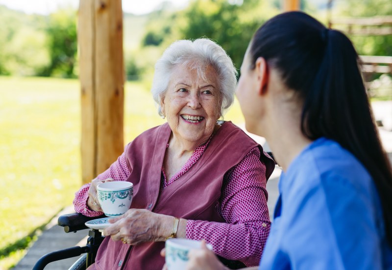 Senior and caregiver chatting over tea outdoors representing home care in Glenview, IL